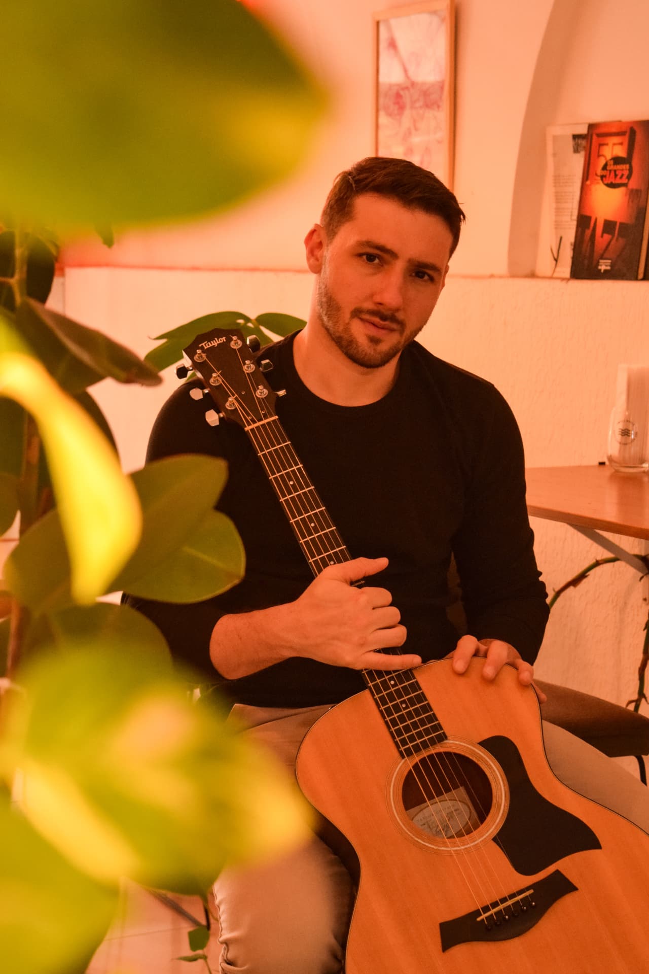 Roger Loeblein com o violão em um ambiente interno de luz quente